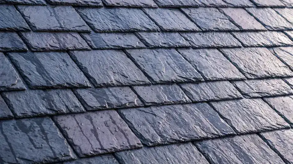 Graduated courses of hand-cut slate, still wet, raking light across the stone